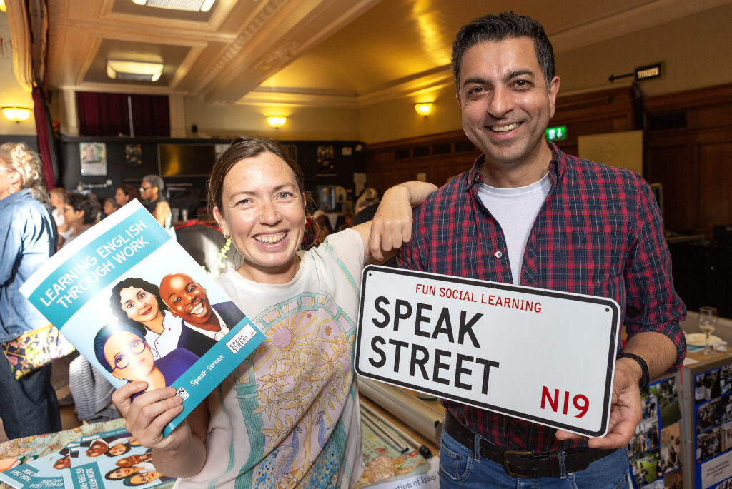 Two people holding up the Speak Street sign 